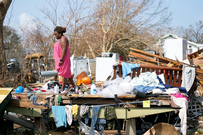 A woman inspects the wreckage of her home after Hurricane Ida