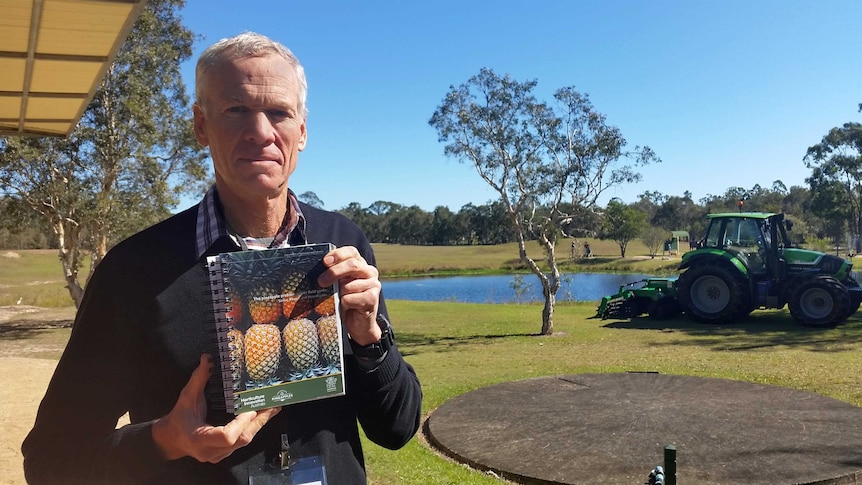 Simon Newett holds a copy of the  Pineapple Problem Solver field guide.