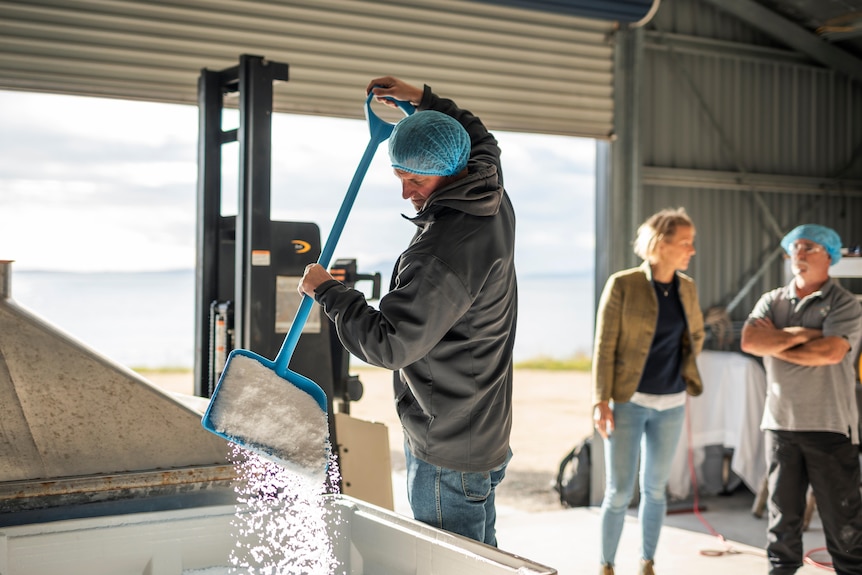 man using spade on bin of sea salt