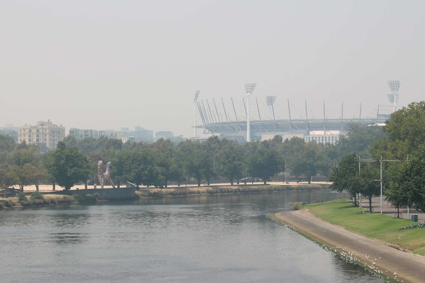 Looking across the Yarra River from Princes Bridge towards the MCG which is shrouded in smoke.