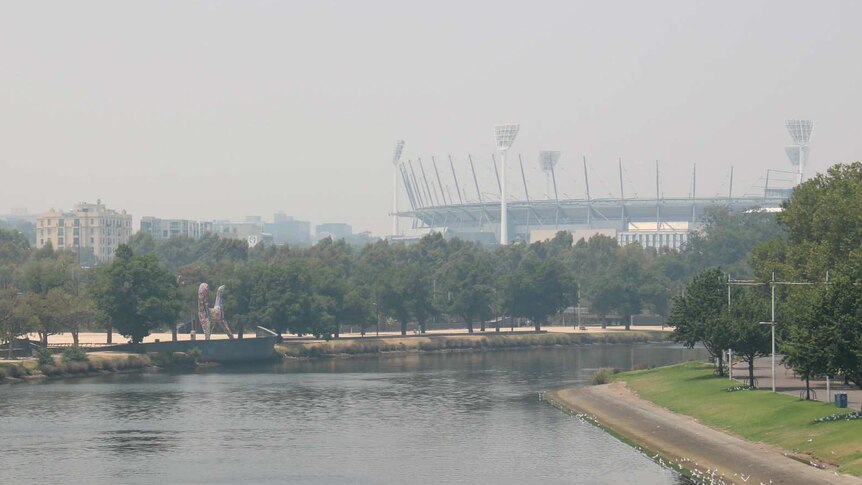 Looking across the Yarra River from Princes Bridge towards the MCG which is shrouded in smoke.