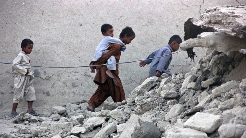 Children pick over earthquake rubble in Pakistan