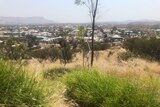 A grassy hill overlooking an outback city.