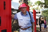 An elderly man standing next to several red doors.