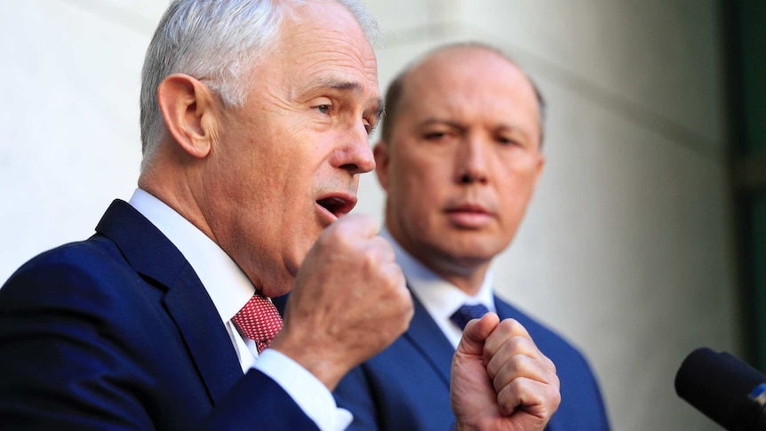 Prime Minister Malcolm Turnbull speaks in Canberra as Immigration Minister Peter Dutton looks on