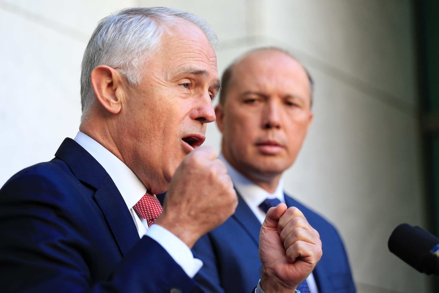 Prime Minister Malcolm Turnbull speaks in Canberra as Immigration Minister Peter Dutton looks on