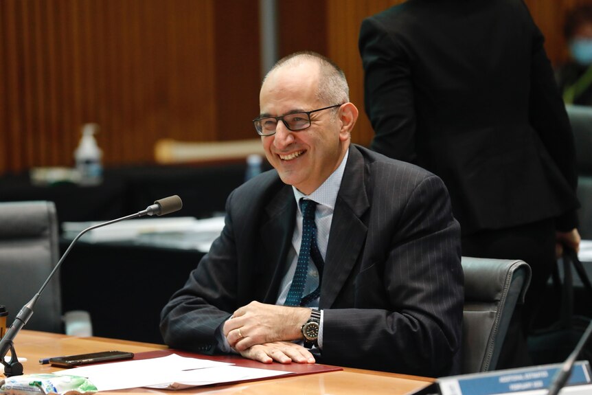 Mike Pezzullo smiles while giving evidence to a parliamentary inquiry 
