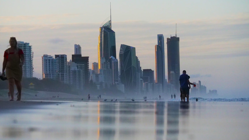 tall towers reflect in water at a beach