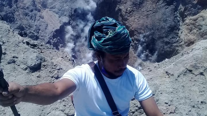 One of the members of the group is seen sitting on the edge of Mount Agung.