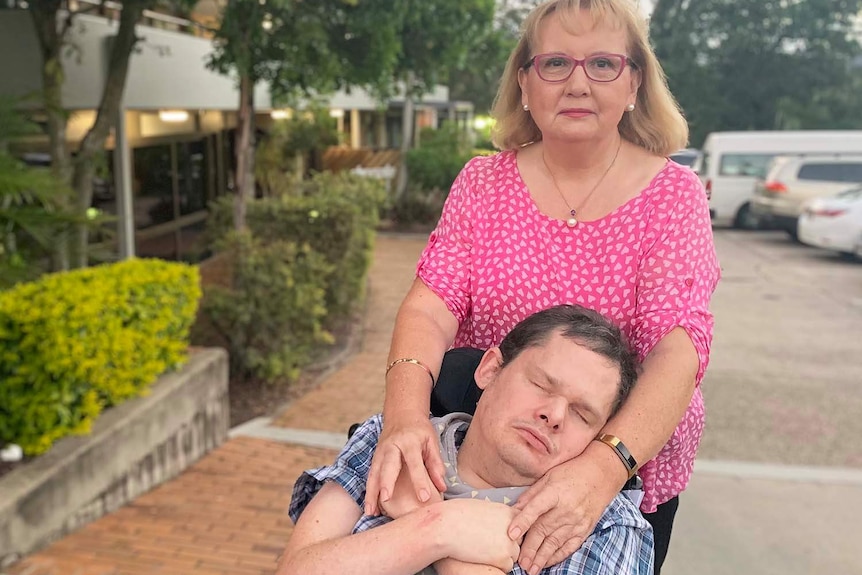 Patricia Dear stands with her arms hugging her son Kearon Dear, who is severely disabled, in Brisbane in April 2019.