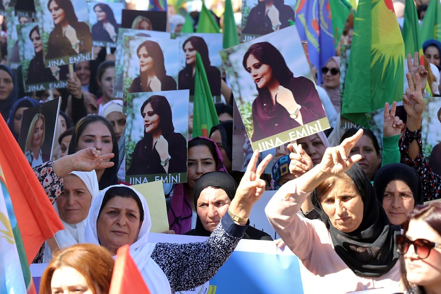 Des Iraniennes manifestent en brandissant des photos de Mahsa Amini.