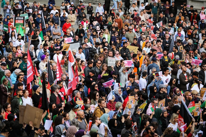 A wide shot of a crowd with posters about protecting Afghanistan.