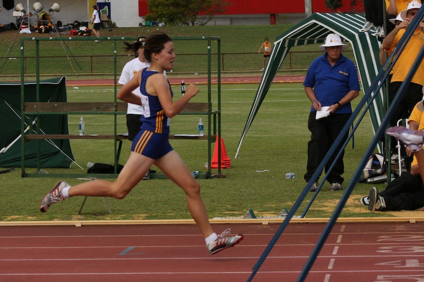 A child runs over the finish line on an athletics track.