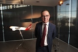 Alan Joyce stands in front of a model plane