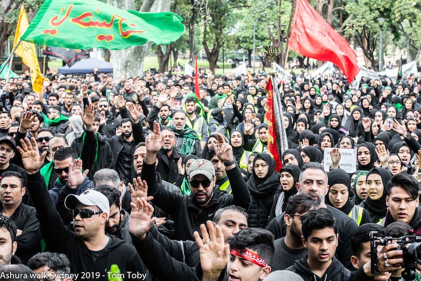 A photo showing thousands during the Ashura procession in Sydney. Many wearing black, holding flags.