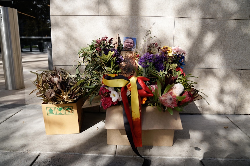 Flowers in a box with a photo of Wayne Morrison