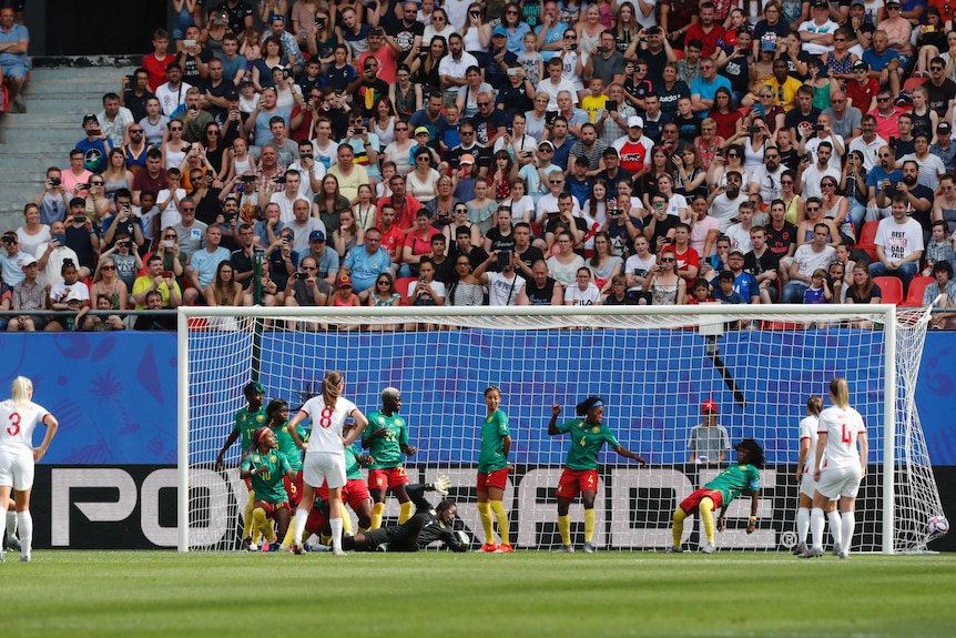 A soccer player scores from a free kick past a queue of defenders on the goal-line.