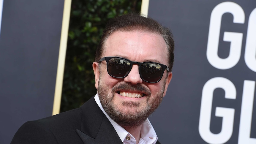 Ricky Gervais in black suit and sunglasses on the red carpet
