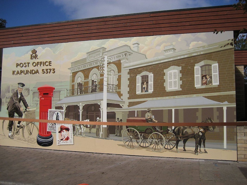 A brown and white Victorian post office mural on a wall, lady in victorian clothing in horse--drawn carriage, man on a bicycle.
