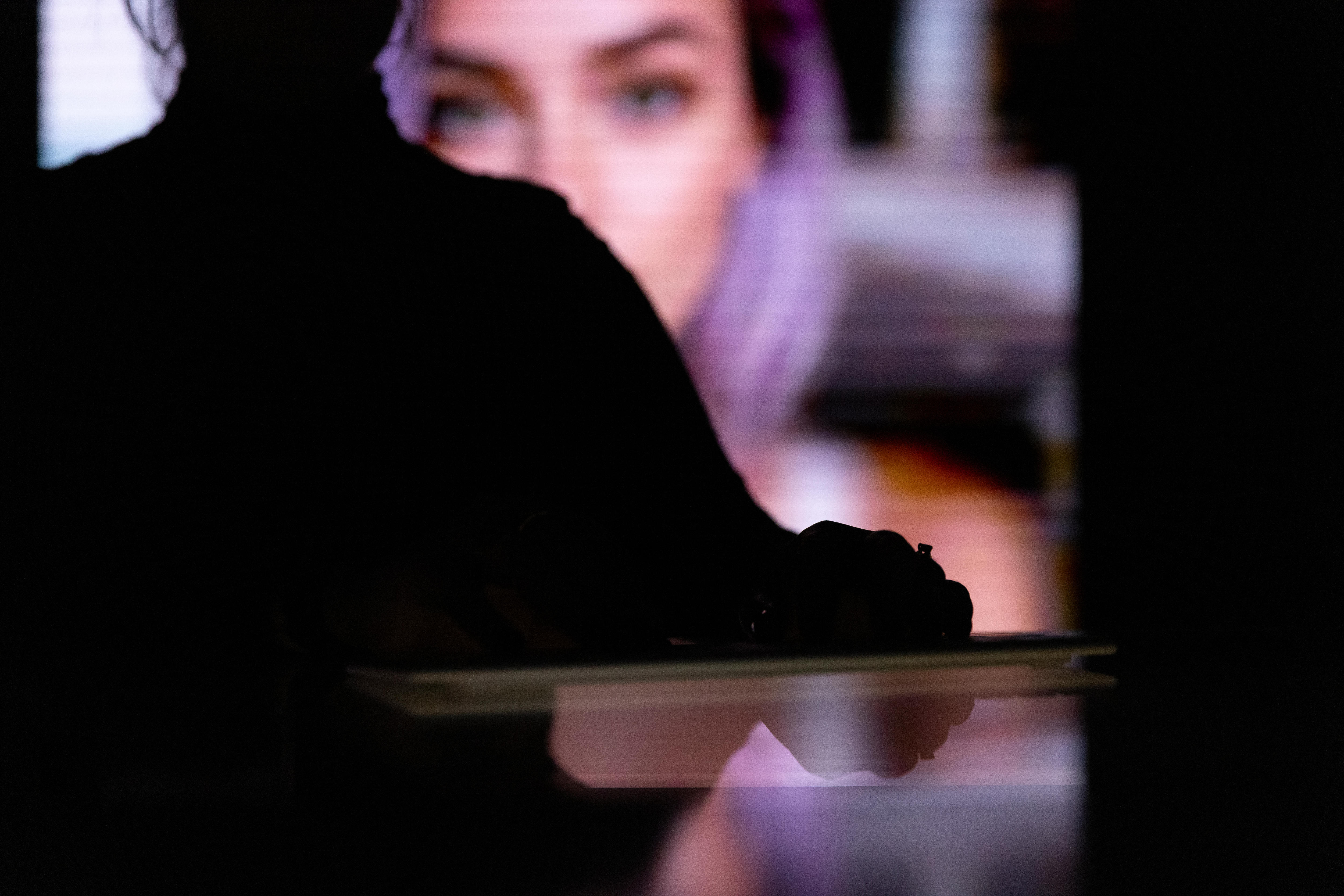 A silhouetted person before a screen with an out-of-focus AI-generated female figure.