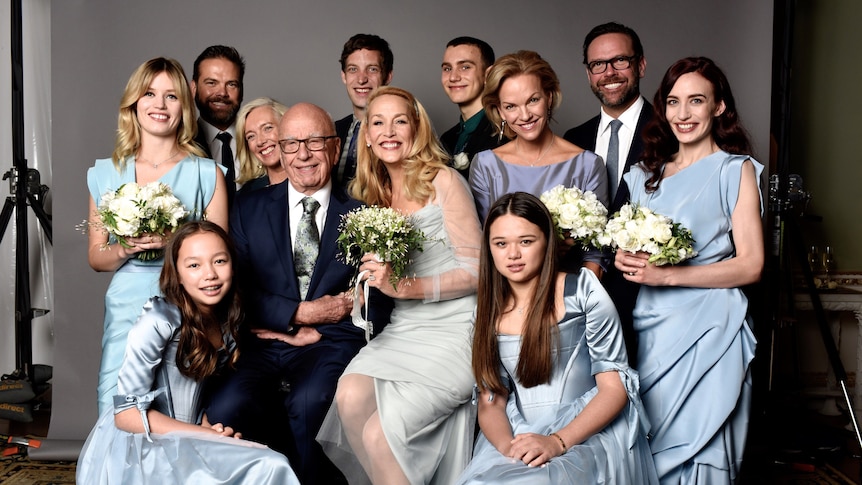 Rupert Murdoch and Jerry Hall sit, surrounded by their children, all the women holding bouquets