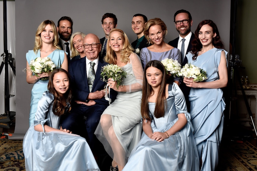 Rupert Murdoch and Jerry Hall sit, surrounded by their children, all the women holding bouquets
