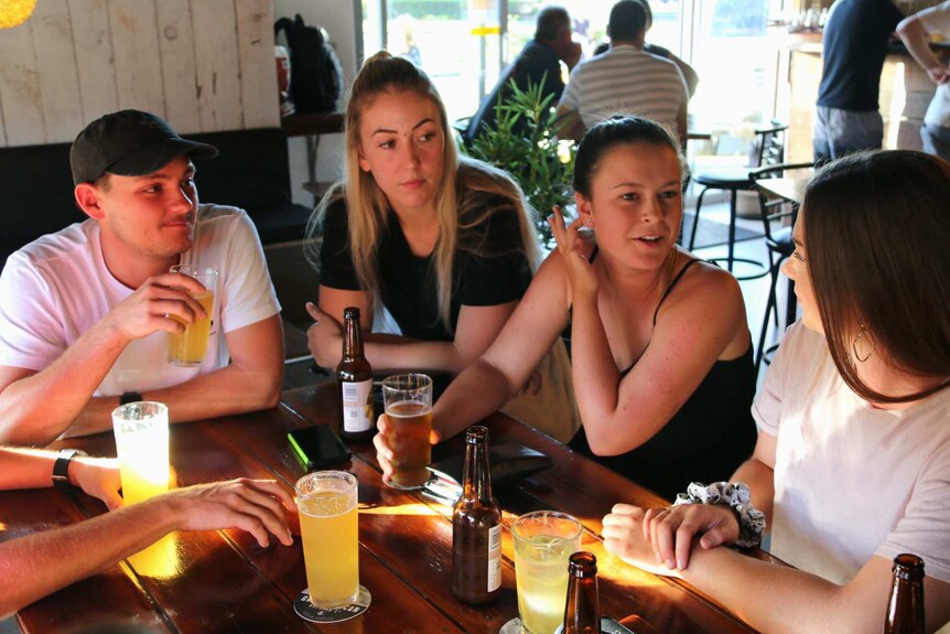 Friends Joshua Wilson, Jasmine Erskine, Courtney Flanders and Alana Scott chat at a craft beer bar.
