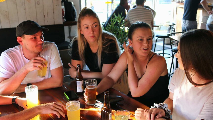 Friends Joshua Wilson, Jasmine Erskine, Courtney Flanders and Alana Scott chat at a craft beer bar.