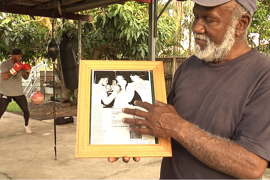Doug holding a old boxing photo of himself.