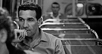 A black and white photo of Charles Perkins as a young man sitting on a bus.