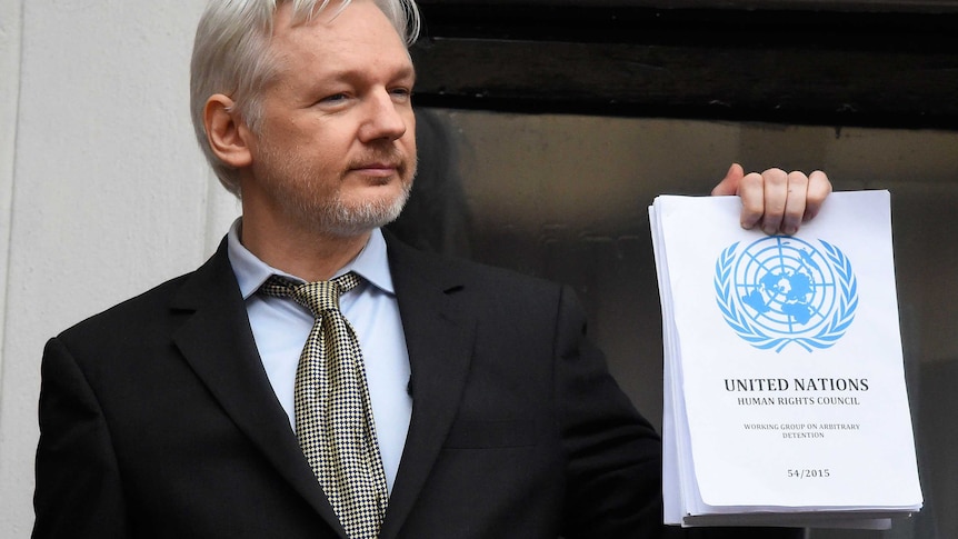 Julian Assange holds a copy of a UN ruling at the Ecuadorian embassy.