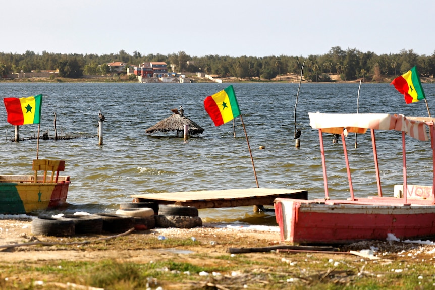 A hut submerged in water and red, yellow and green flags on the bank. 