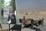 Man rides donkey past Karzai poll poster