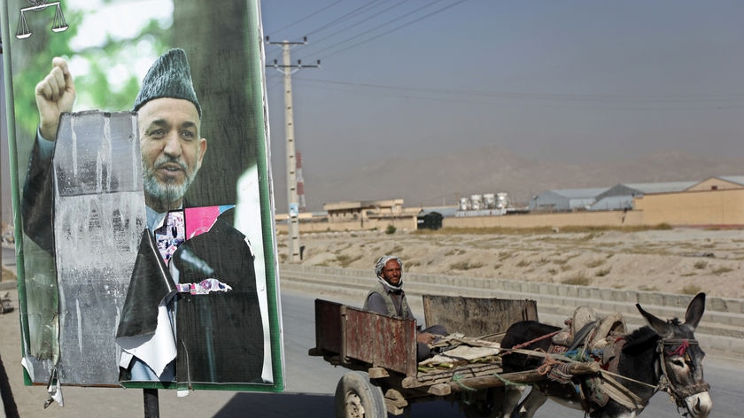 Man rides donkey past Karzai poll poster