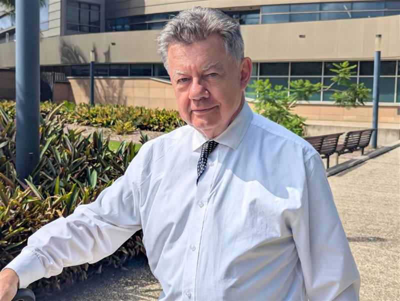 Un hombre de mediana edad con cabello corto y gris viste camisa y corbata mientras sale de un juzgado.
