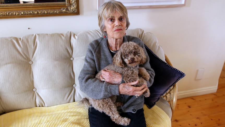 Katriona sits on the couch with her dog, Fudge.