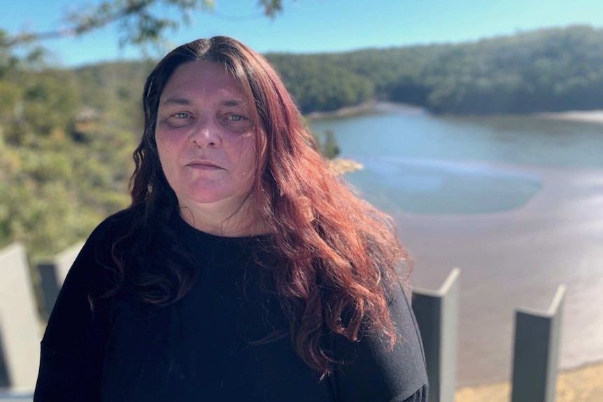 A woman standing near a dam river.