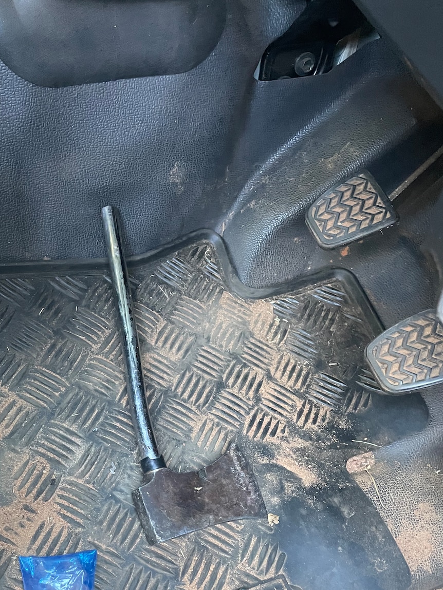 A small axe at the foot of a driver's car seat.