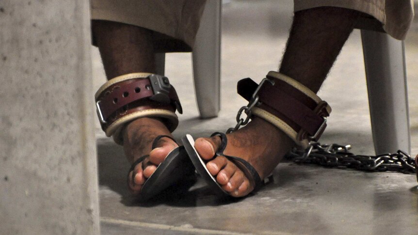A Guantanamo detainee's feet are shackled to the floor