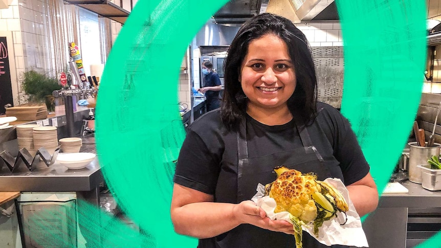 Chef Rupal Bhatikar holding a roasted cauliflower in a commercial kitchen in a story about changing careers in your 30s.