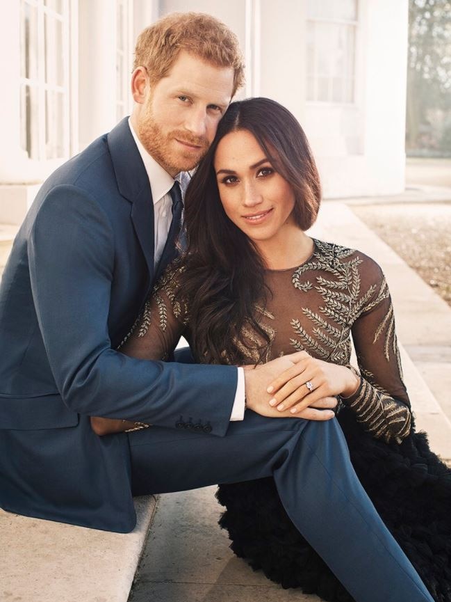 Prince Harry and Meghan Markle sit together, holding hands, with Ms Markle's engagement ring visible on her hand.