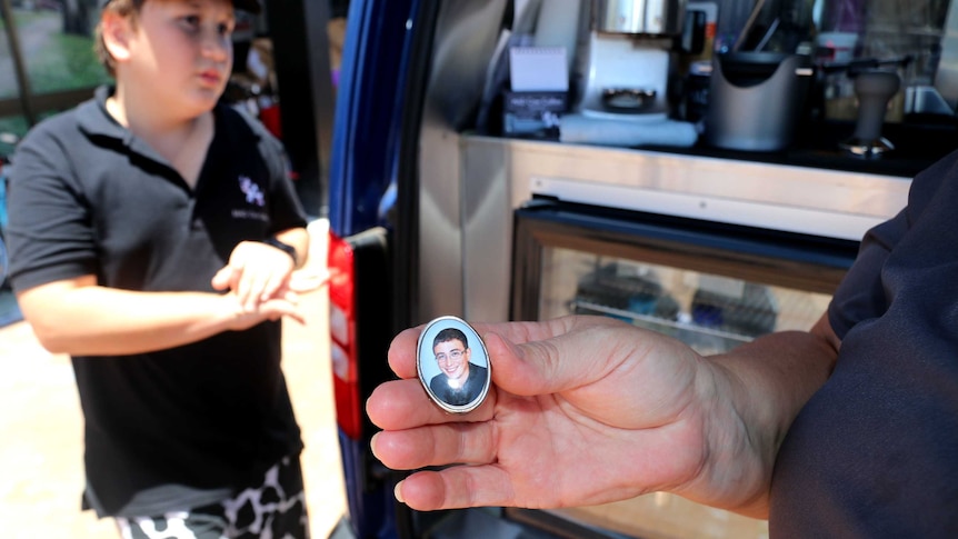 A locket photo is being held up in front of a coffee van.