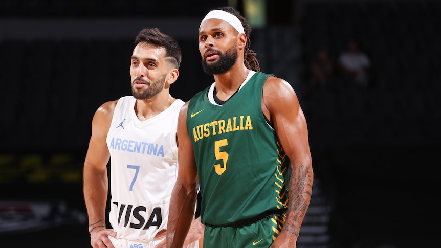 A male Argentine basketball players stands alongside an Australian opponent.