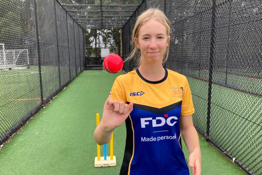 Jade Allen twirls a ball in her hand wearing a yellow and blue top