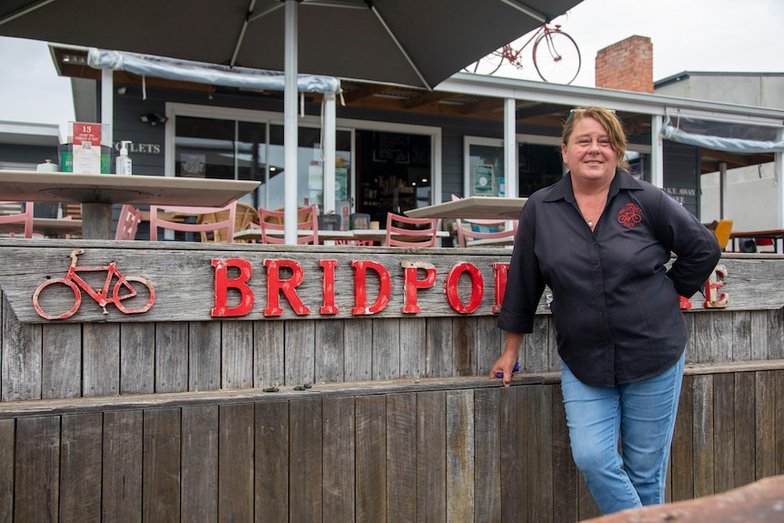 A woman stands in front of a cafe's outdoor dining area