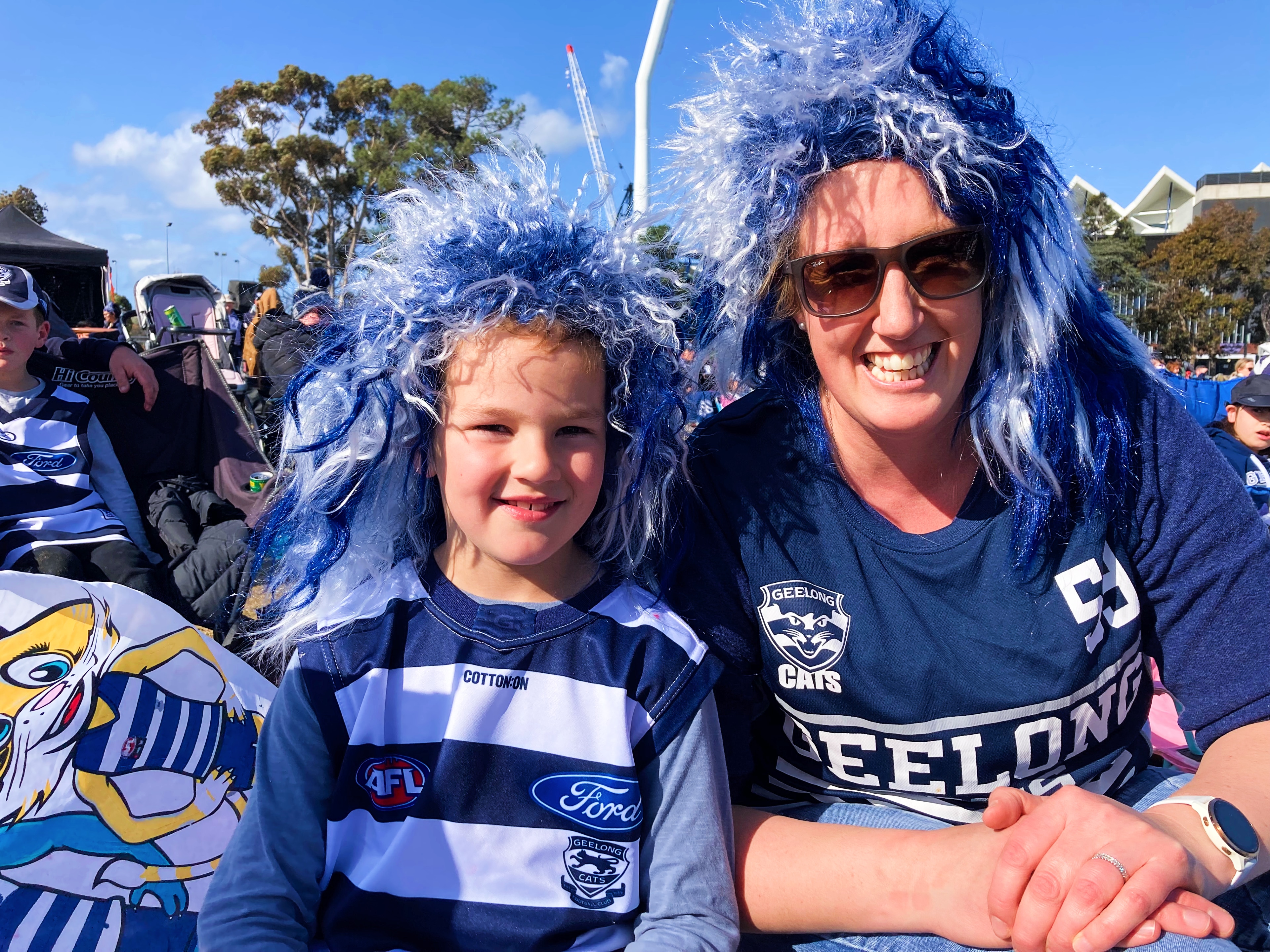 A young child and woman decked out in Geelong Cats merch and smiling.