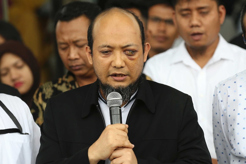 Novel Baswedan talks during a press conference. One eye can be seen swollen and closed.