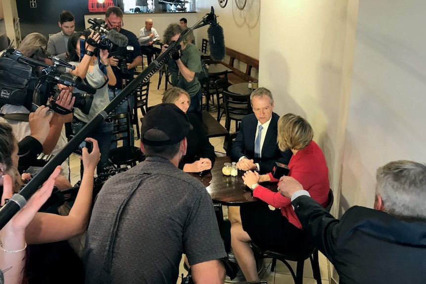 Two people sit at a table surrounded by media.