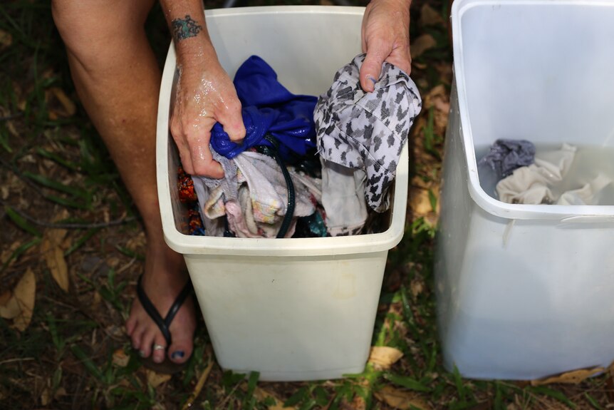 Hands washing clothes in plastic tubs