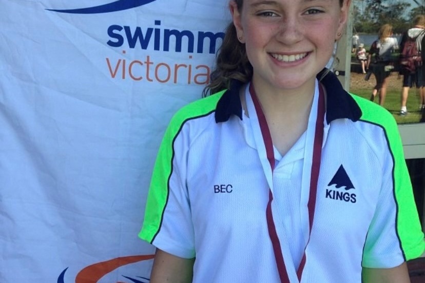 A young Bec Henderson smiles at the camera wearing a medal around her neck.